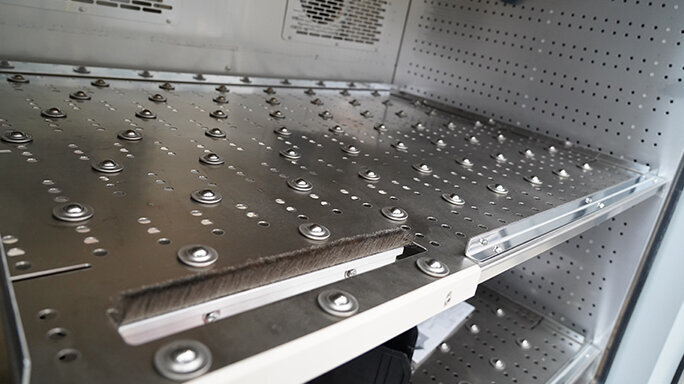 Heavy-duty inserts with ball rollers and a brush in a climate cabinet with fans on the rear wall.